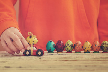 Child hands playing easter egg on car on wooden table. Holiday concept.