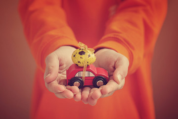Child hands holding easter egg on car on orange background. Holiday concept