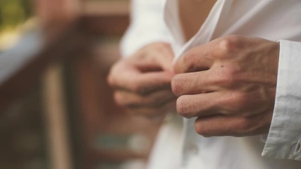  Male hands wear white shirt outdoor. Man dressing close-up. - Powered by Adobe