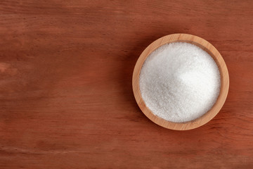 White sugar, shot from above on a dark rustic wooden background with a place for text