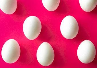 Pattern made of white eggs on bright pink color background. Minimal concept