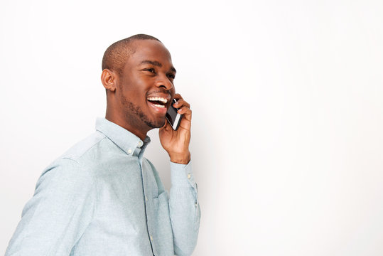 Side Of Happy Young Black Man Talking With Cellphone By White Background