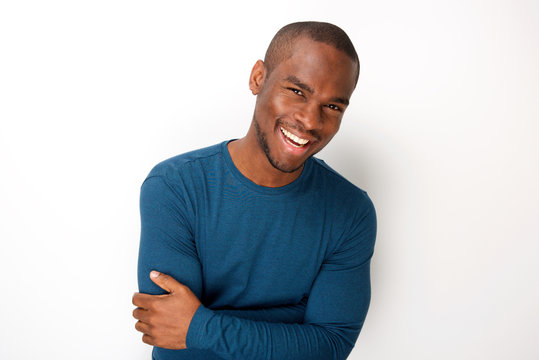handsome young black man smiling with arms folded by white background