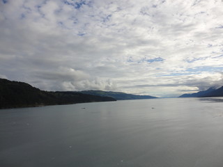 Passage in the Pacific Ocean between two mountain ranges. Calm peaceful waters flowing slowly under a cloudy sky.