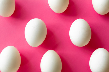 White eggs on fuchsia color background, top view