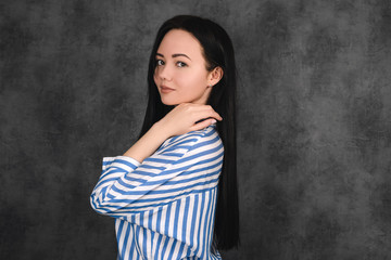 Fototapeta na wymiar Brunette girl in striped shirt portrait, business portrait on grey dark background