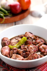 A tasty squid dish with soy sauce in white bowl. Adobong Pusit from Philippines.