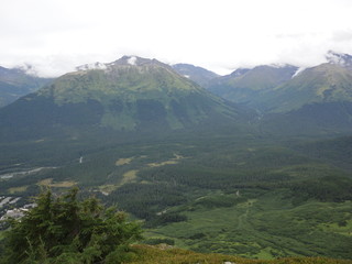 Fototapeta premium View from atop a mountain in the wilderness of Alaska. Peaks and ocean stretching off into the sky and clouds