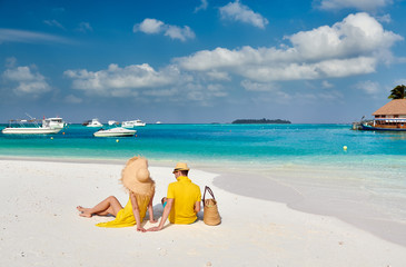 Fototapeta na wymiar Couple in yellow on tropical beach at Maldives