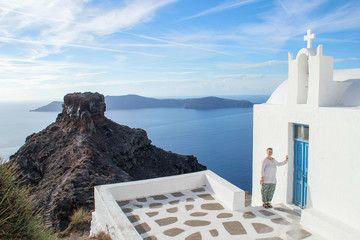 Santorini Island, Greece - November 17, 2016: A young girl tourist in white clothes is smiling next...