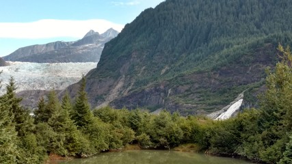 Mendenhall Glacier Juneau Alaska. Mendenhall Glacier flowing into Mendenhall Lake in between mountains with Nugget falls. Perfect tourist location