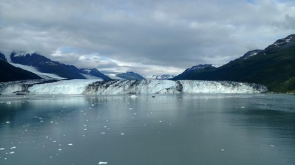Harvard Glacier at the end of College Fjord Alaska. Wide glacier carving its path to the sea. Mountains peaks water and clouds
