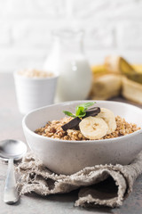 Healthy breakfast bowl. Granola with chocolate and banana on gray table. The concept of healthy nutrition and diet.