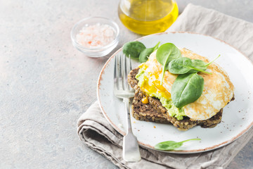 Sandwich with avocado, egg and spinach on white wooden background. Healthy diet breakfast