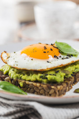 Sandwich with avocado, egg and spinach on white wooden background. Healthy diet breakfast