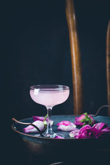 Summer refreshment drinks. Light pink rose cocktail, with rose wine on dark background. With rose flowers. Copy space