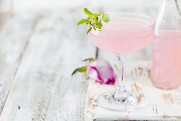 Summer refreshment drinks. Light pink rose cocktail, with rose wine on a white table. With rose flowers. Copy space