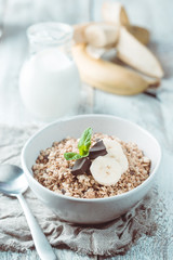 Healthy breakfast bowl. Granola with chocolate and banana on white wooden table. The concept of healthy nutrition and diet.