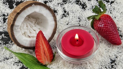 Obraz na płótnie Canvas Coconut and strawberry on the background of coconut flakes, cosmetics and accessories for spa and aromatherapy