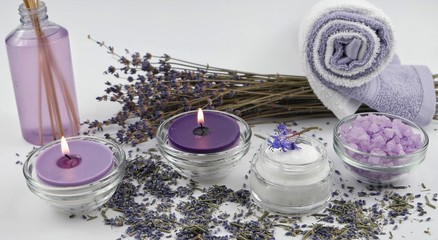 Obraz na płótnie Canvas Burning aromatic candles, dry lavender, cosmetics on the white background. Spa and aromatherapy accessories.