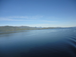 Calm Pacific Ocean in the inside passage in Alaska blue sky meets mountains and blue sea in a peacefully clear view