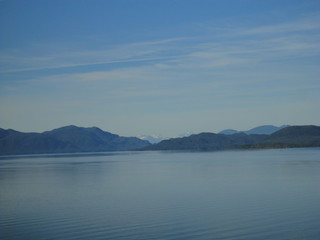 Calm Pacific Ocean in the inside passage in Alaska blue sky meets mountains and blue sea in a peacefully clear view