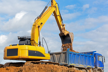 Excavator construction equipment unloading sand into tipper truck
