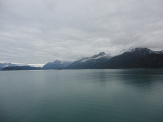Mountain Filled horizon on the pacific ocean. Inside passage Alaska with glaciers at the peaks under a cloudy sky