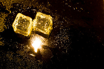 ice cubes and water drop on light golden background.