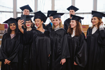 Multi ethnic group of graduated students taking selfie