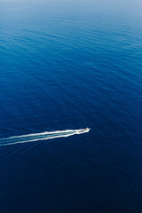Fototapeta premium Yacht at the sea in Italy. Aerial view of luxury floating boat on transparent turquoise water at sunny day. Summer seascape from air. Top view from drone. Seascape with motorboat in bay.