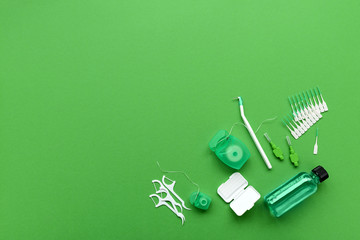 Different tools for dental care on green background. Toothbrush, cleanser, floss, flossers, wax for...