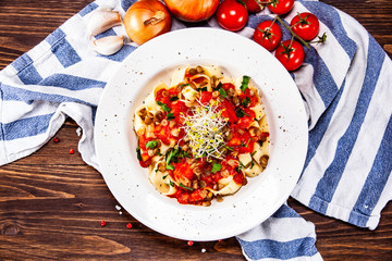 Pasta with tomato sauce and vegetables on wooden table