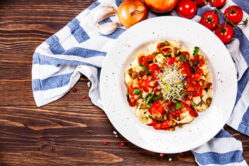 Pasta with tomato sauce and vegetables on wooden table