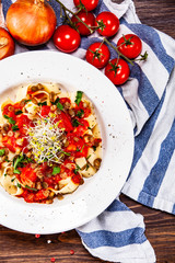 Pasta with tomato sauce and vegetables on wooden table