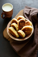 Fried patties or pies filled green onion and eggs on dark wooden background. Pirozhki Russian tradition food.
