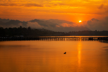 Fototapeta premium Summer sunset or sunrise over the Mon Bridge is the long wooden bridge. Attanusorn Bridge. Is the route of the villagers cross to Mon village, Sangkhla Buri, Kanchanaburi, Thailand 24 Jan 2019