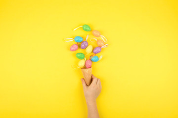 Easter composition, greeting card with child hand, lightbox text Happy Easter, colored decorative eggs on color background.