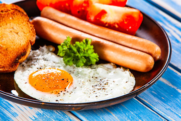 English breakfast - fried egg, sausages, toasts and vegetables