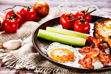 Breakfast - fried egg ,toasts,bacon, and vegetables