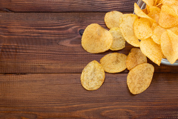 Crispy potato chips in bowl on wooden background. Top view with copyspace