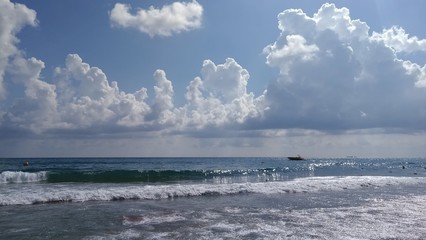 Clouds over the sea waves with a motor boat on the horizon.