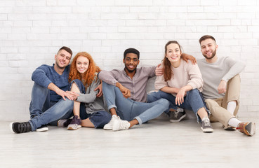 Diverse students sitting on floor and looking at camera