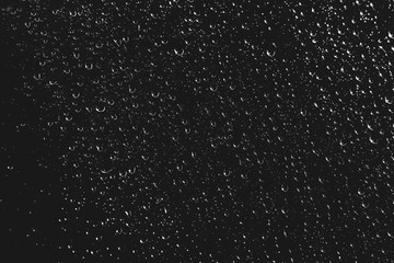 Dirty window glass with drops of rain. Atmospheric monochrome dark background with raindrops. Droplets and stains close up. Detailed transparent texture in macro with copy space. Night rainy weather.