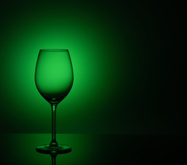Empty wine glass is on acrylic glass, on a green background