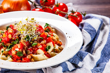 Pasta with tomato sauce and vegetables on wooden table