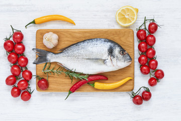 Fresh dorada fish with spices on wooden cutting board. Healthy food concept. Top view, copy space.