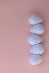White eggs on the background in pink pastel color. Small plastic toy eggs. Kids toys. Minimalism food concept. Easter concept.Pink and white background.