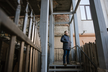 Fototapeta premium A man with a beard in a warm winter jacket poses for advertising men's clothing in the winter. Advertising of men's clothing