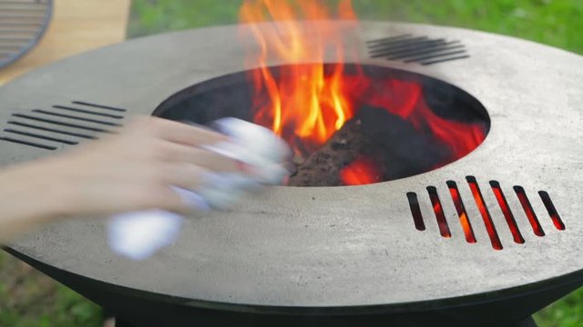 Preparing a new grill for use. Linseed oil on a white cloth. Use of oil for the first calcination of the frying surface. Female hand with a manicure. Happy people having camping and bbq party outdoor.